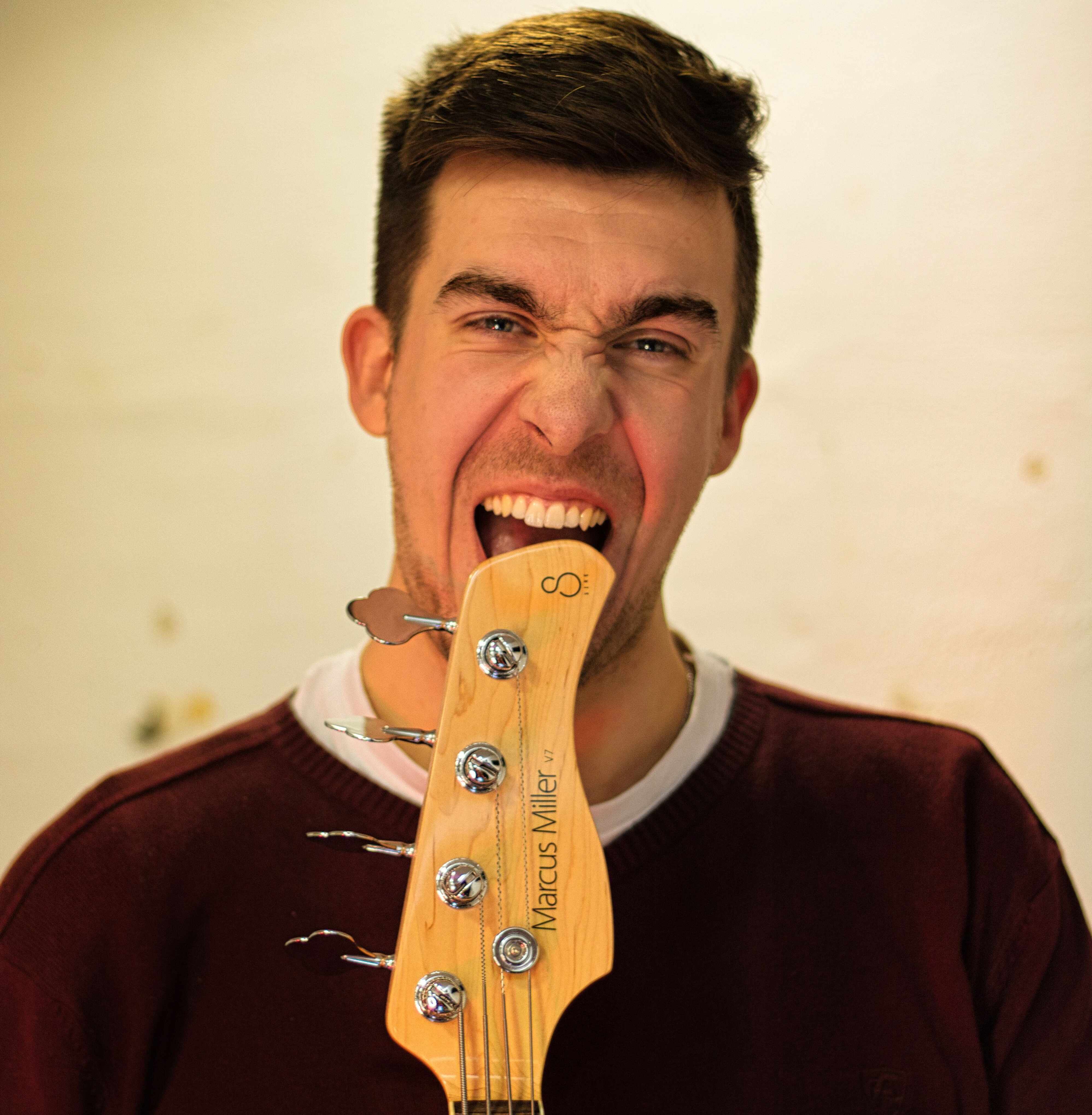 Tom spielt auf der Bühne Gitarre und lächelt, vor ihm ein Mikrofon